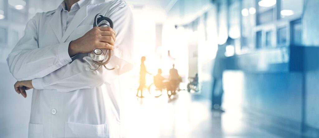 Doctor standing in a well-lit hospital corridor with energy-efficient LED lighting, holding a stethoscope.