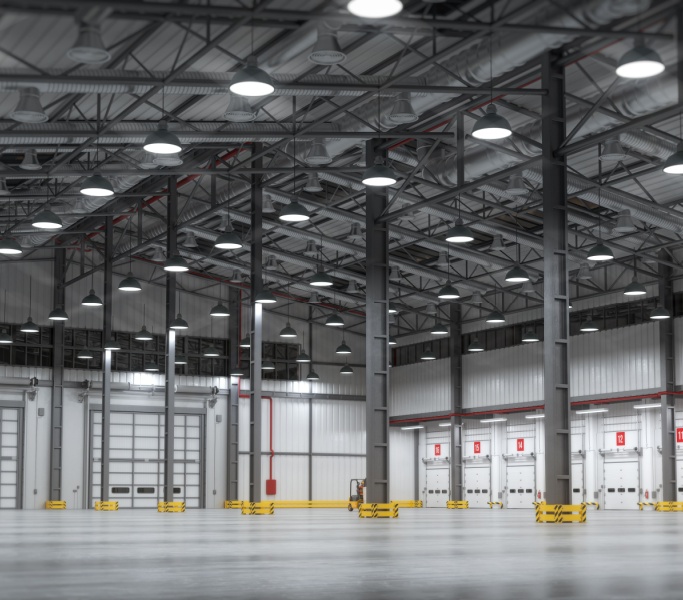 An industrial warehouse equipped with high bay LED lighting, featuring large open spaces and high ceilings with metal structural elements.