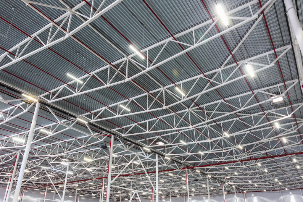 Industrial warehouse ceiling with LED high bay lights installed for energy-efficient lighting.