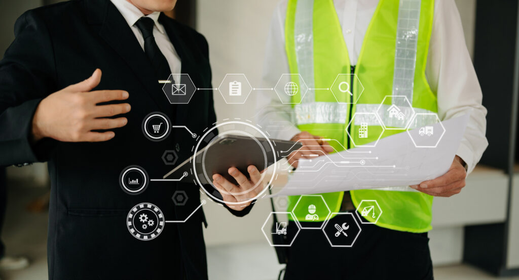 Professionals reviewing a commercial building project with a tablet and blueprints, surrounded by digital icons representing project management and technology integration.